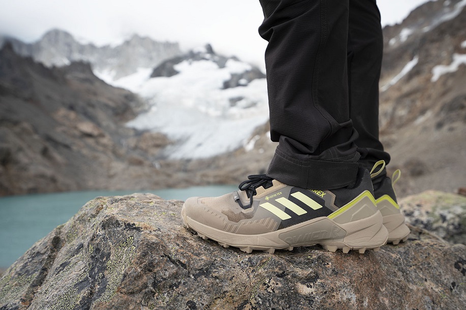person with adidas terrex standing on a cliff