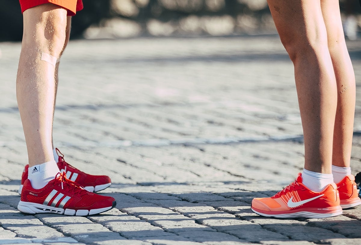 two people standing across each other one with nike sneakers on the other with adidas