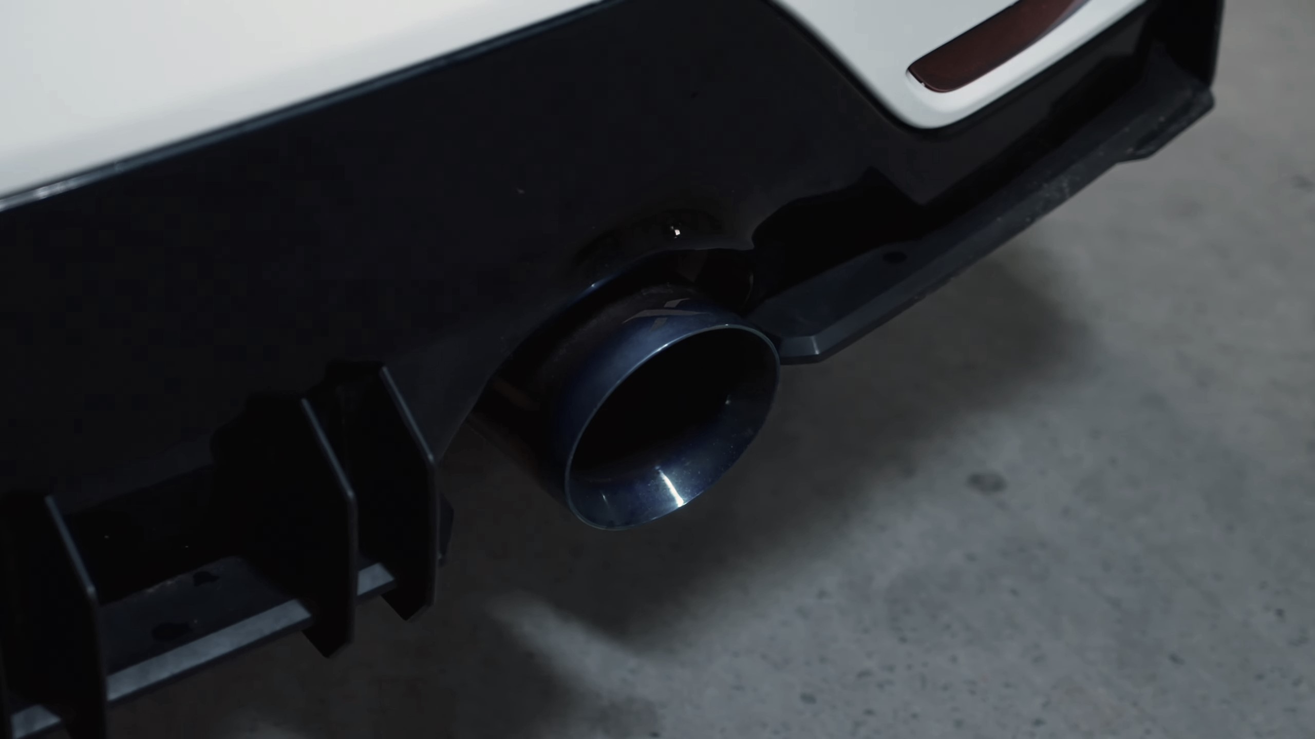 Close-up of car XForce aftermarket exhaust pipe on white sportscar.